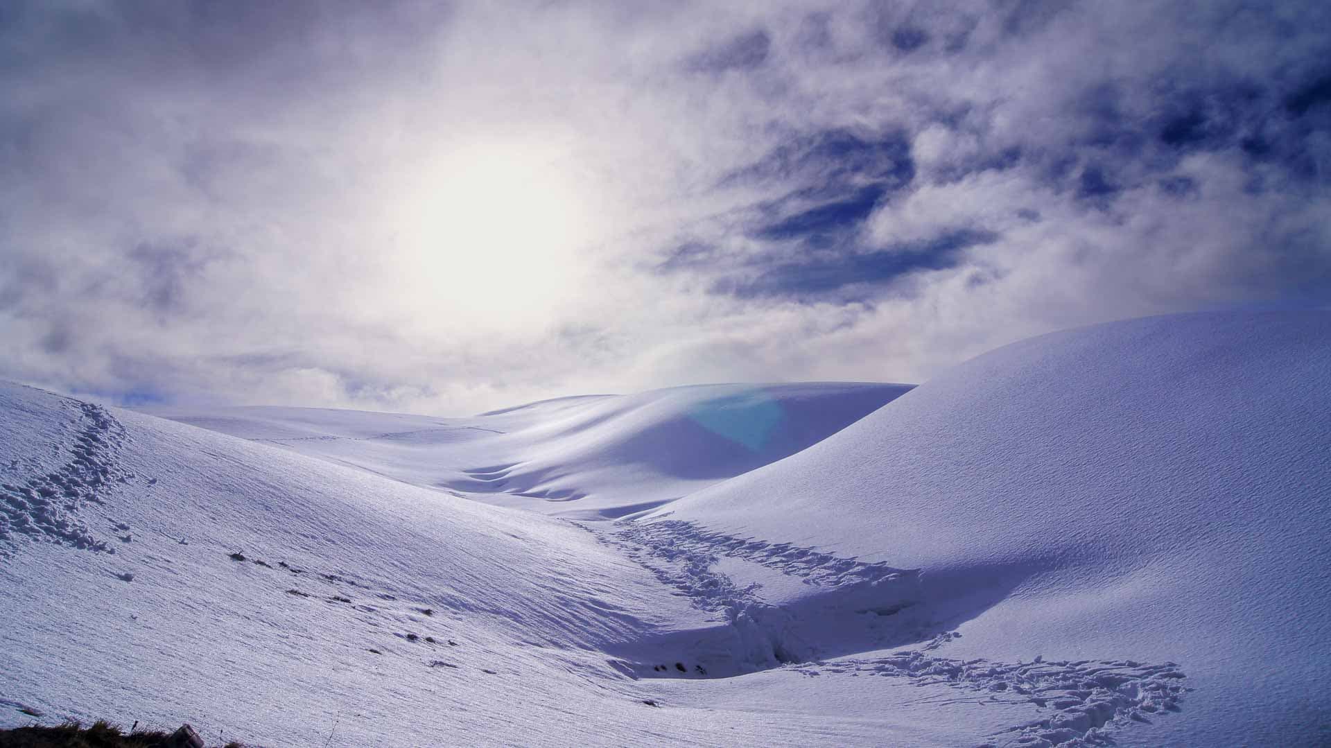 Footprints in the snow with a clouded sun