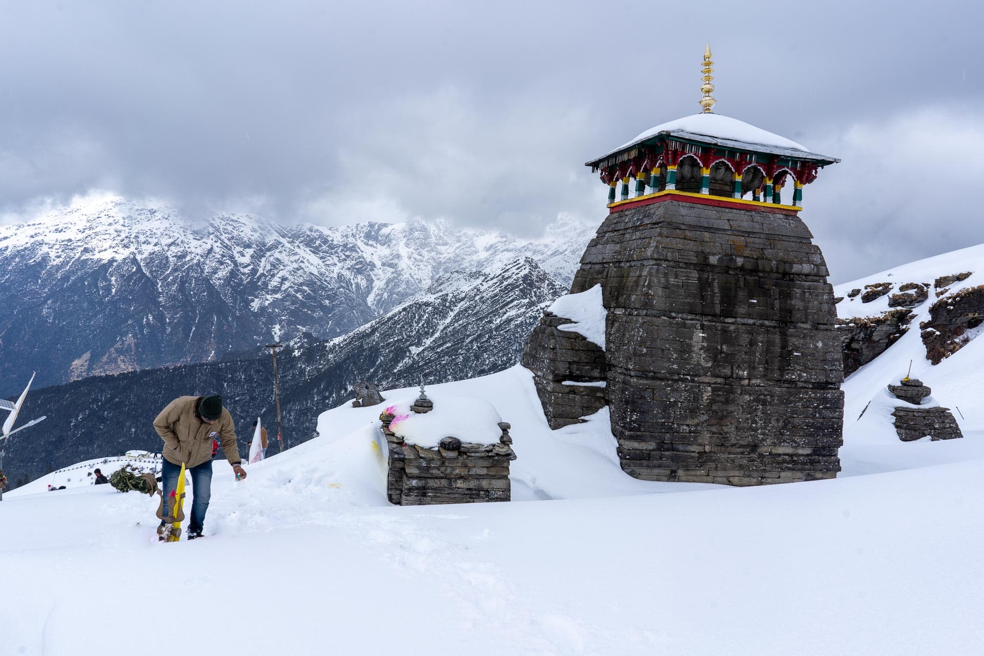 A snow covered Tungnath temple with a person standing next to it