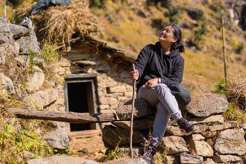 A lady next to a traditional hut