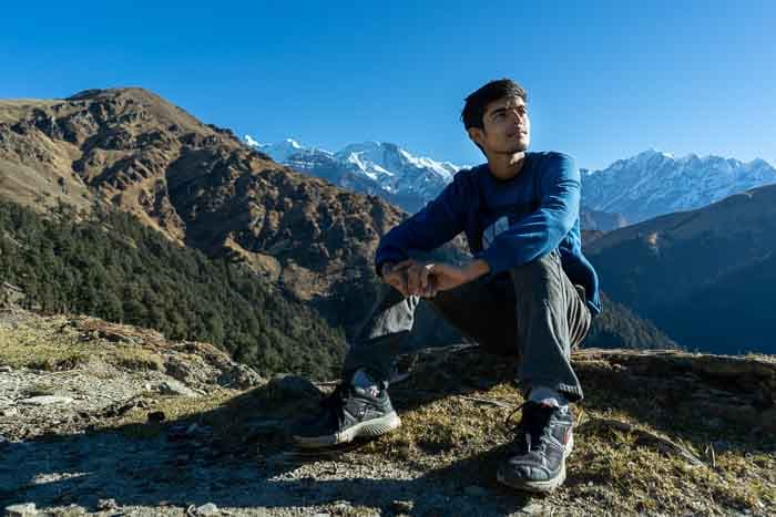 Young person sat on a rock with a mountainous backdrop