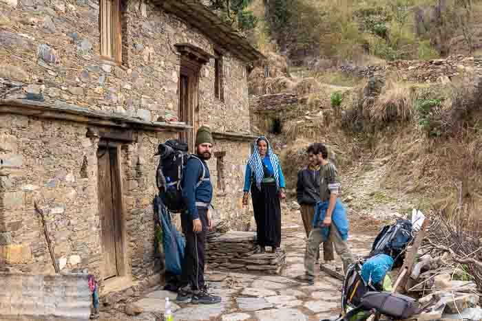 Four travellers standing near a rustic traditional home