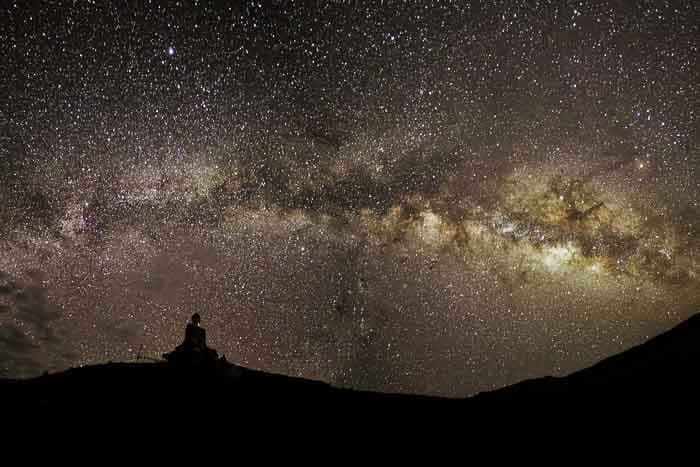 Silhouette of a person on the horizon with a backdrop of the Milky Way